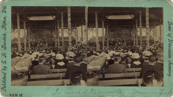 Stereograph of the interior of the Tabernacle during the Monona Lake Assembly. The assembly, Madison's annual Chautauqua, was held on the site of the present-day Olin Park. The Tabernacle was built by J.H. Findorff and it was the largest room for gatherings in Wisconsin. Printed on the stereograph: "Published by E.H. Burdick, Milton, Wis. Gems of Wisconsin Scenery." Hand-written at foot: "View of Interior of Tabernacle, Monona Lake."