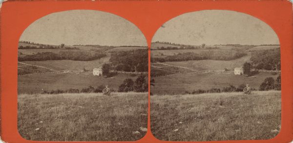 Stereograph of an elevated view of a farm. A man is sitting on the hill in the foreground with his arm on one knee, gazing at the view. There is a house, people, animals, fences and fields in the valley. Hills and trees fill the horizon.<p>Handwritten on back: "Return to Dr. Syverud. The old parsonage. Father K.K. Syverud viewing same. Taken about year 1867. Built by Uncle Nels Syverud year 1856. Farm consisted of 40 acres in Government(?) time. When Father bought it he added to 140 acres. Farm now 180 acres. Situated in Sec 34 and 35 township(?) of Blue Mds. Dane Co. Wis. This is where your Great Grand father died. Own by my father. Now own by me and while I was home. And. K. Syverud."</p>