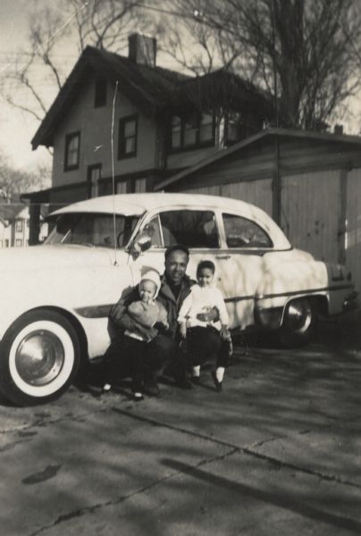 Lewis Arms posing with his daughters, Mamie and Rita, by his automobile. They are in front of their house at 847 Williamson Street.