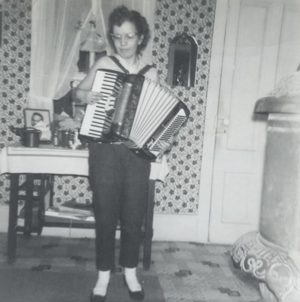 The granddaughter of Nellie Arms playing the accordion, probably in Nellie's home.