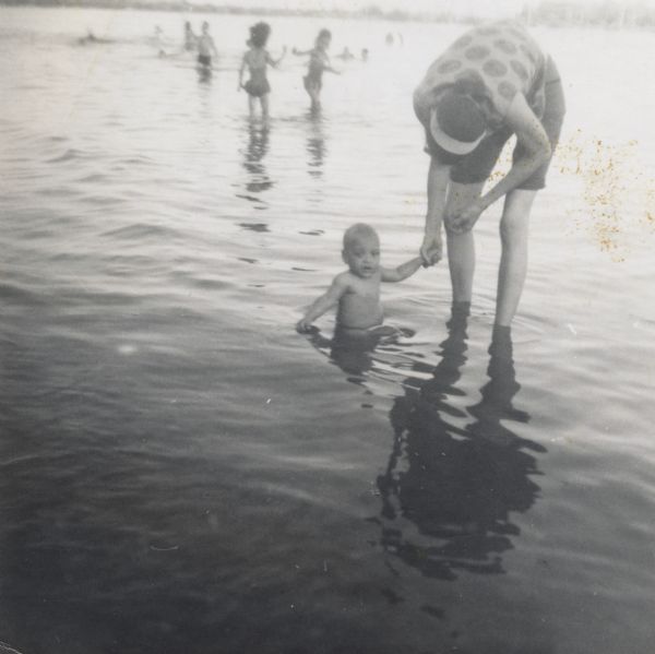 Baby Paul Arms playing in the water at a beach with his mother LuRay. His sisters Rita and Mamie are in the background.