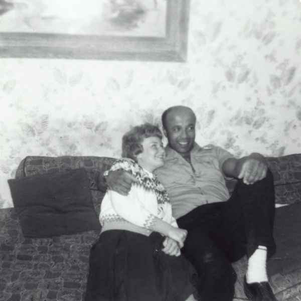 Janet Sauk and Lewis Arms sitting on a sofa together. Lewis has his arm around Janet.