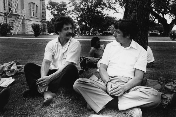 Mayor Paul Soglin and Tom Hayden chatting at the Conference on Alternative State and Local Public Policies held on the St. Edward's University Campus. They are sitting in the grass, Soglin in his stocking feet, and Hayden leaning against a tree. He was on the Madison City Council, 1968 to 1978 and the Mayor of Madison, 1973-1979, 1989-1997, and 2011 to the present. Hayden was a civil rights and anti-war activist. He served a combined 18 years in the California State Assembly and State Senate.