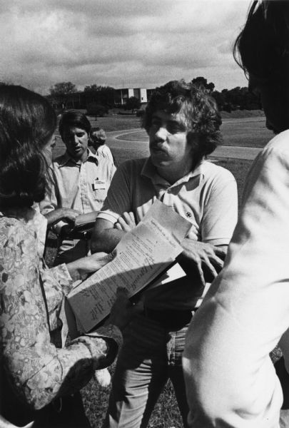 Activist Sam W. Brown, Jr., having a conversation with people outdoors at the Conference on Alternative State and Local Public Policies held at the St. Edward's University Campus. Brown was the Colorado State Treasurer from 1975 to 1977.