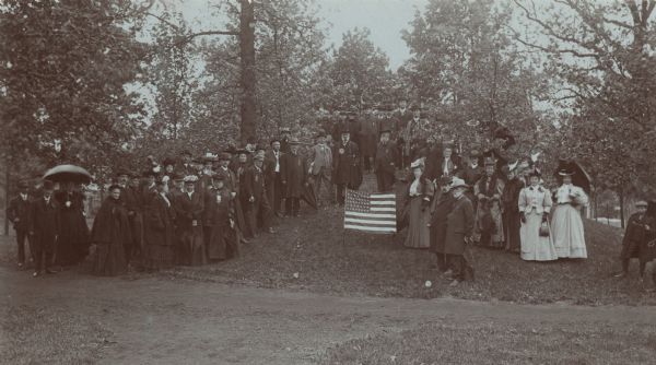 The Wisconsin Archeological Society attending the unveiling of the Cutler Indian mound marker at Cutler Park. Mrs. William H. Anderson, President (?) of the Waukesha Women's Club, at the left of the marker. Dr. S.D. Peet, Dr. Reuben G. Thwaites, Superintendent of the State Historical Society of Wisconsin, Dr. W.O. Carrier, Rolland L. Porter and Dr. W.L. Rankin at the left of the marker.