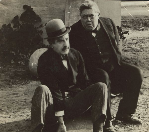 Film still - exterior with two men sitting.
