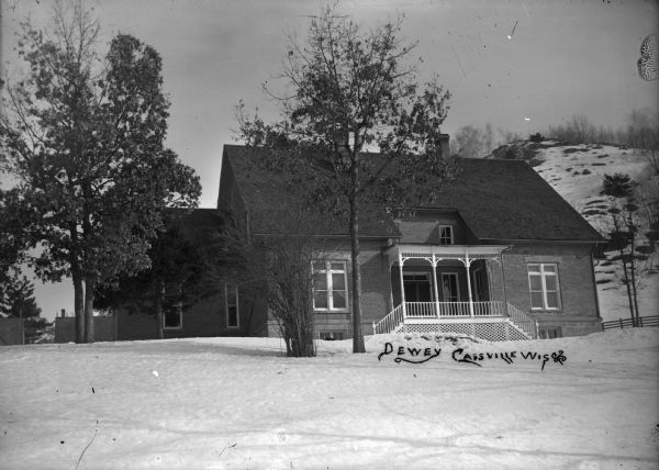 View of exterior of house with snow on the ground. There is a steep hill in the background. The house was built after Nelson Dewey's death.