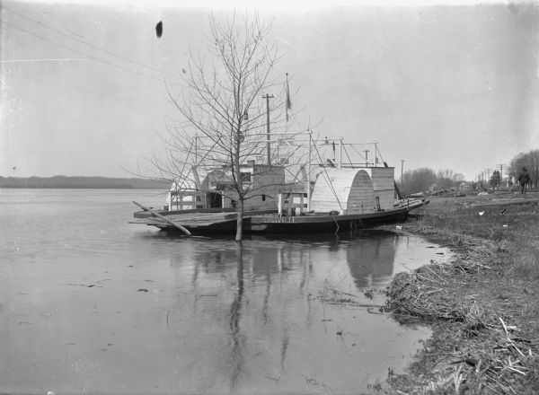 Ferry tied up at the Cassville dock. A number of men are standing along the shoreline.