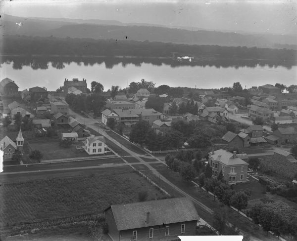 View over town, including hotel and church, towards the Mississippi River. The far shoreline and bluffs are in the distance.