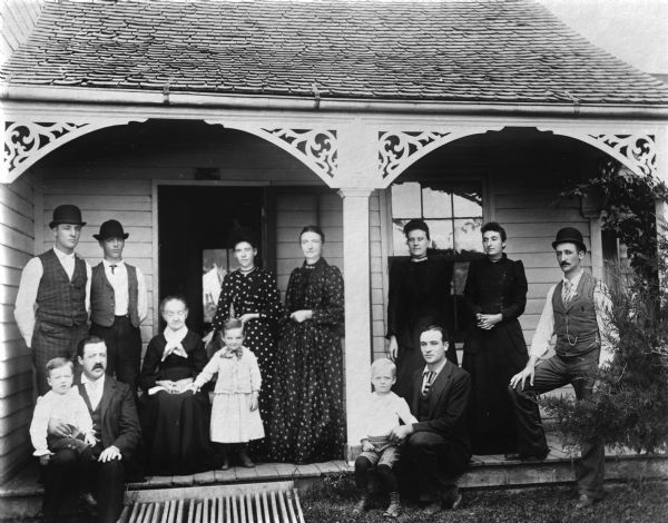 Several generations of a family posing on the porch of a house.