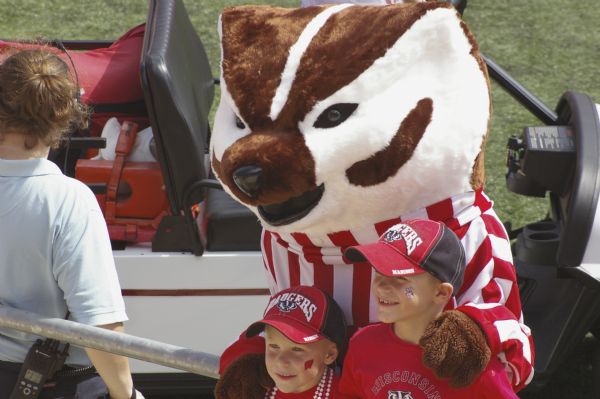 Two young Wisconsin Badger fans pose with Bucky Badger mascot at Camp Randall Memorial Stadium.