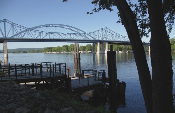 View of two bridges, a pier, and trees along the Mississippi River.