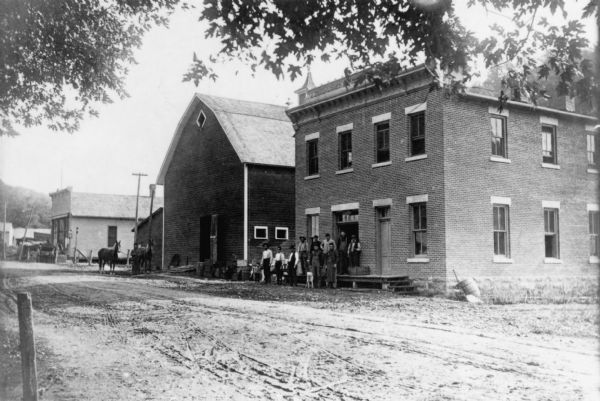 A group of men standing outside the Potosi Brewing Company bottling house. Next to the brick building is a barn that served as the brewery's stables.