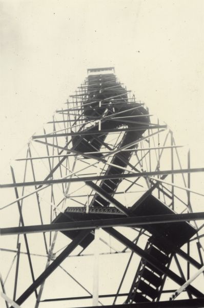 Fire tower at Pigeon Lake Boys' Camp, a summer camp sponsored by the Recreation Department of the Work Projects Administration. Thirteen boys associated with Neighborhood House did odd jobs in their communities to help pay their camp expenses; the rest was paid by the Community Union Camping Fund. The caption in the scrapbook reads, "One of the highlights of the camping period was the five mile hike to the fire tower. It was the desire of every boy to climb the tower and thus become a member of the 'Squirrel Club.' Neighborhood House boys assisted Camp leaders in taking small boys over to the tower. They were also instrumental in encouraging the younger boys to climb the tower."