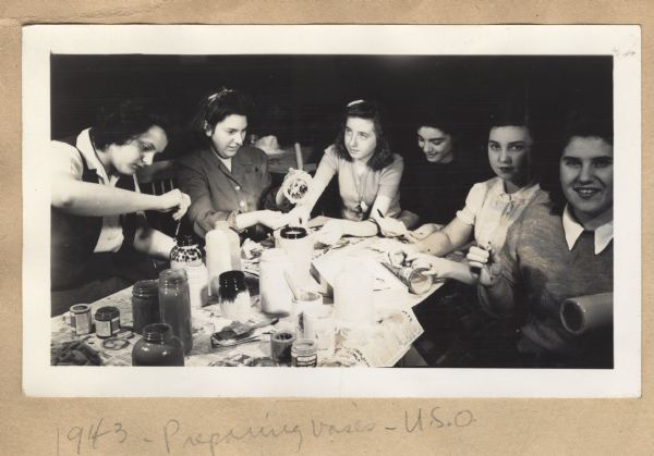 Image from a scrapbook kept by Neighborhood House, with women painting vases for United Service Organizations (USO) use. Groups at the settlement house worked on various service projects during the 1930s and 1940s.