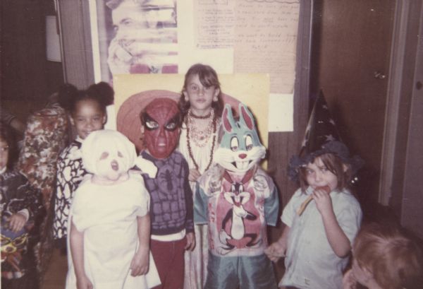 Group portrait of children in Halloween costumes, including a ghost, Spiderman, and Bugs Bunny, probably at Neighborhood House.