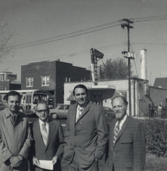 Group of four men, including William Dyke, third from right, posing outdoors across the street from Josie's Lounge, an Italian restaurant located at 906 Regent Street in the Greenbush neighborhood.