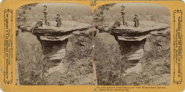 Three hunters and their dog posing on the top of Stand Rock. Text at right: "Wanderings Among the Wonders and Beauties of Wisconsin Scenery."