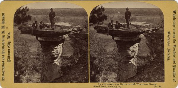 Stereograph of three men at the top of Stand Rock. One man is standing holding his rifle, while the two other people are sitting. Text at right: "Wanderings Among the Wonders and Beauties of Wisconsin Scenery."