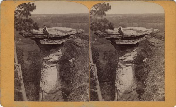 Elevated view of a man sitting on the ledge on Stand Rock.