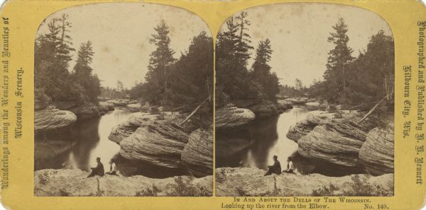 Elevated view looking upriver towards two men sitting on rocks at Devils Elbow. Text at bottom reads: "In and About the Dells of The Wisconsin. Looking up the river from the Elbow."