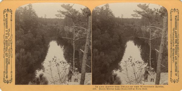 View from above of two girls holding hands on a cliff overlooking Mirror Lake. Text at right: "Wanderings Among the Wonders and Beauties of Wisconsin Scenery."