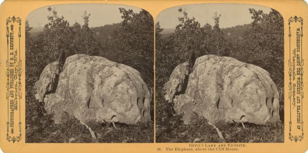 View of young man sitting on the top of Elephant Rock. Text at right: "Wanderings Among the Wonders and Beauties of Wisconsin Scenery."