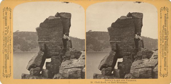 Two men climbing Cleft Rock on East Bluff. Devil's Lake is in the background. Text at right: "Wanderings Among the Wonders and Beauties of Wisconsin Scenery."

