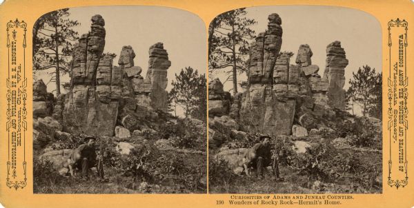 A man holding a rifle sits with his dog in front of a rock formation. Text at right: "Wanderings Among the Wonders and Beauties of Wisconsin Scenery."