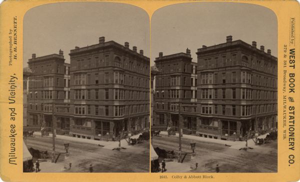 Elevated stereograph view published by West Book and Stationery Company depicting a Milwaukee Street. Features a large corner building. In the lower left corner, there is a sign for a dentist office.