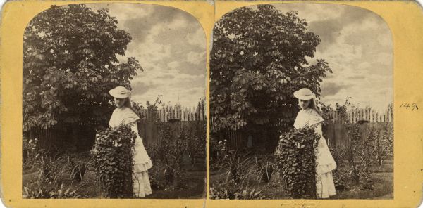 A woman posing in a garden at William H. Metcalf's Residence.