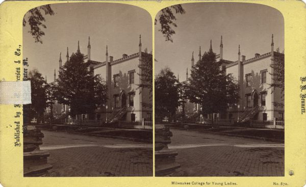 Exterior view from across cobblestone street of the Milwaukee College For Young Ladies. The view of the main entrance is obstructed by a tree.