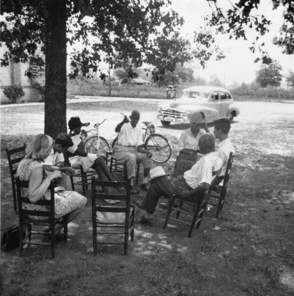 Group of people sitting in chairs while attending out-of-doors classes during Freedom Summer at the Freedom School, Priest Creek Baptist Church.