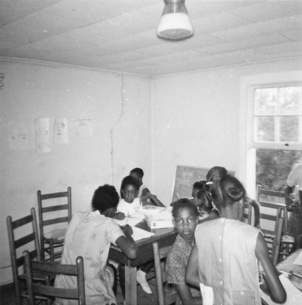 Students sitting at tables in a Freedom Summer school in Palmer's Crossing at Priest Creek Baptist Church. Classes were usually held out-of-doors because of the heat.