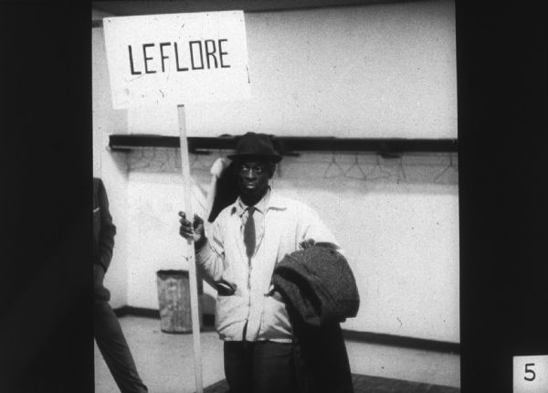 A man holds a sign, likely referring to Leflore County in Mississippi, at a Mississippi Freedom Democratic Party (MFDP) function.