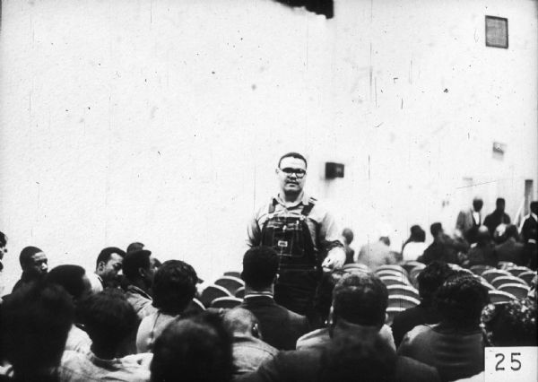 Lawrence Guyot, civil rights activist, stands and addresses a seated group.