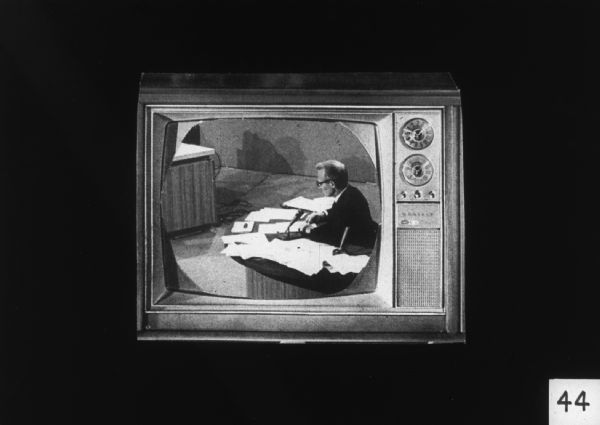 A television set displays an image of a man seated at a desk covered in papers and microphones, likely at the 1964 Democratic National Convention where the Mississippi Freedom Democratic Party (MFDP) sought to be seated as the delegates from Mississippi.