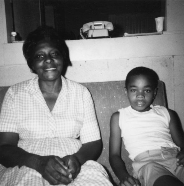 A woman and a young boy pose for a civil rights volunteer.
"Often one of Mrs. Thompson's nieces or nephews would come[?] to breakfast in order to have something to eat."