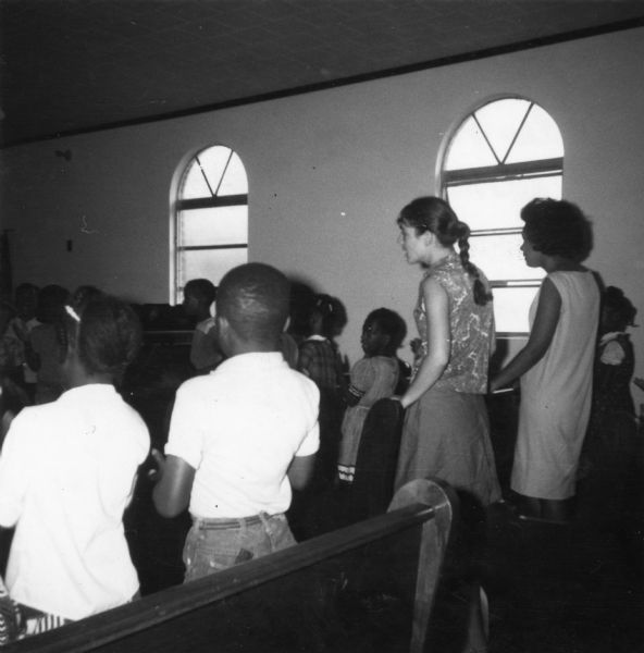 Image of a Freedom School classroom taken by a civil rights volunteer.  Students are seated in what appear to be pews.<p>
"Freedom School - Freddie Green, young woman on the extreme right, taught with me in Freedom School, explained the MFDP (Mississippi Freedom Democratic Party) at our second summer freedom meeting, and led our house discussion with eight domestic maids at Mrs. Alexander's.  She was trying to educate herself by reading since her schooling had been inadequate."