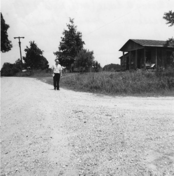 A man stands on the road outside a home shortly after civil rights volunteers depart from canvassing.<p>"Leaving a house (on the right) after canvassing. Because Summit was far more rural than Hattiesburg or McComb, the people were understandably less receptive to our first knock-on-the-door."