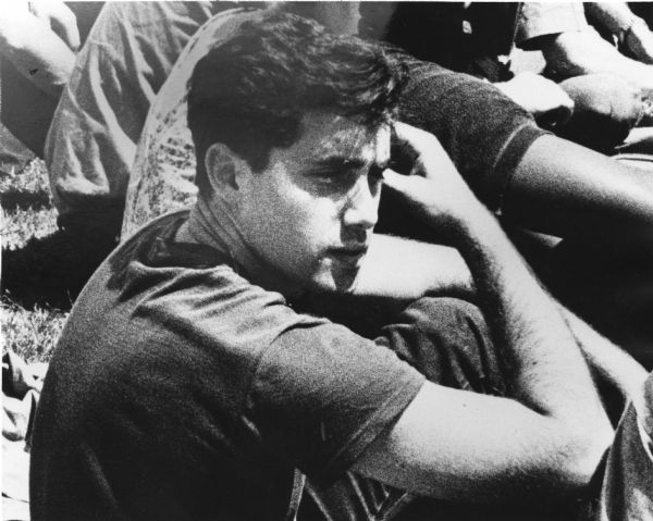 Andrew Goodman seated on the ground in a group of people, wearing a dark t-shirt. Andrew Goodman was a civil rights activist and volunteer for the Freedom Summer project. He, along with James Chaney and Michael Schwerner, was murdered in the summer of 1964.