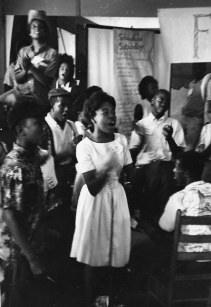 A group claps and sings at the Freedom School Convention during the Freedom Summer civil rights project.