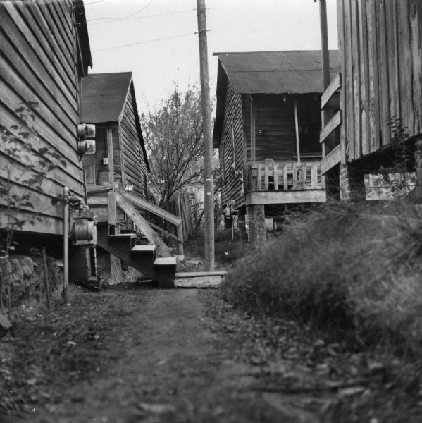 "This path from the alleyway to the outhouse is flooded when it rains — note the 'bridge' from the bottom porch step to the opposite bank."<p>Griffin Alley houses 12 families in 6 buildings. All residents share 2 hydrants and 4 toilets.
