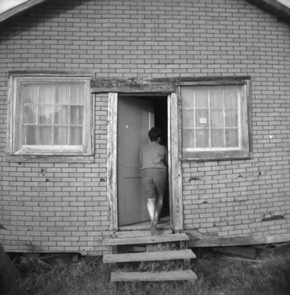 A woman walks up steps and through a door into a Freedom House, used by civil rights workers.