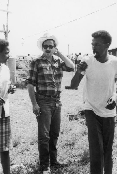 An image taken at a barbeque hosted by E.W. Steptoe for SNCC staff in McComb County, Mississippi. The man in the center wearing a hat is Marshall Ganz, a staff member of SNCC (Student Nonviolent Coordinating Committee). The man on the right is Jesse Harris, SNCC organizer and project director for McComb County.
