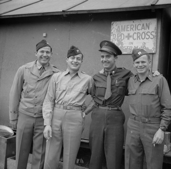 G. Robert Mowerson (left), Red Cross Director and Robert Doyle (third from left), War Correspondent, posing with Captain O.S. Allen of Columbus, Georgia, and Captain Elmer G. Boyer of Lansing, Michigan, at Camp Cable, near Brisbane, Australia. The sign behind them reads, "American Red Cross in Australia." In his notes, Doyle calls the four of them, the "Sad Shack Group."