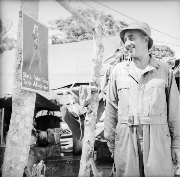 Private Leopold Blaha, a barber from Milwaukee, Wisconsin, looks at a poster with a pretty woman depicted on it that urges the soldiers to take their Atabrine. The camp was located on Kiriwina Island, in the Solomon Sea, New Guinea (present day Papua New Guinea). Atabrine was an effective anti-malaria drug that was not popular with the troops due to the bitter taste and side effects such as yellow skin, headaches, nausea and vomiting. Yet Atabrine was effective, if only the men could be made to take it. To ensure that the medication was actually swallowed by the soldiers, medics or NCOs from the combat units stood at the head of mess lines to carefully watch the soldiers take their little yellow tablets.
