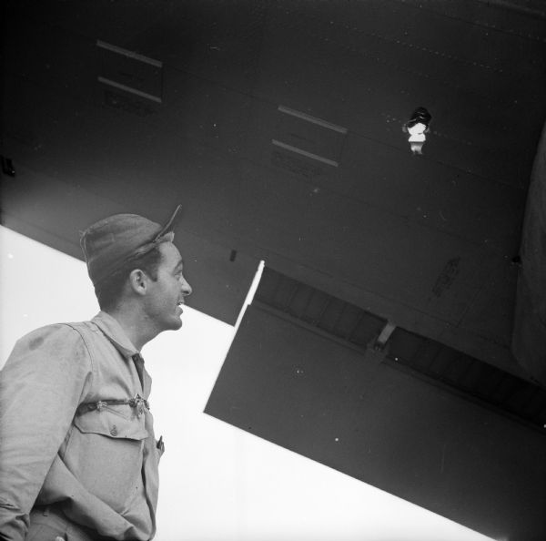 Ralph Boyce of <i>YANK</i>, the Army Weekly magazine, looks up at damage to a warplane at Wards Drome (5 Mile), an airfield near Port Moresby, New Guinea (present day Papua New Guinea). Robert Doyle notes that this photograph was taken by Sergeant Dick Hanley of <i>YANK</i>, the Army Weekly magazine, with Doyle's camera.
