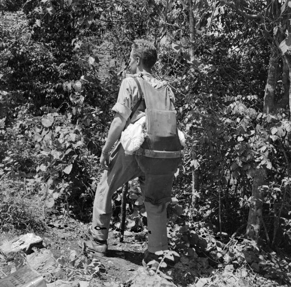 Major Arthur L. Post of Milwaukee, Wisconsin, was shot down on June 20th, 1943 and rescued on September 28th, 1943, after 101 days in the jungle. Here Post is showing Robert Doyle the seat cushion emergency kit exactly like the one he landed with in the jungle. It was attached to his parachute and contained the only food and medicine he had until he found an indigenous village. He also had a walking stick to help him walk with his injured knee. The military base where this image was taken was located near Port Moresby, New Guinea (present day Papua New Guinea). Robert Doyle was not allowed to publish Post's story at that time. It was finally published in January, 1947, by the <i>Milwaukee Journal</i>. Major Post intended to write his own story, but was killed in a test airplane on August 25th, 1944, before he had the chance.