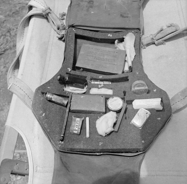 Major Arthur L. Post of Milwaukee, Wisconsin, was shot down on June 20th, 1943 and rescued on September 28th, 1943, after 101 days in the jungle. Here is the seat cushion emergency kit exactly like the one he landed with in the jungle. It was attached to his parachute and contained the only food or medicine he had until he found an indigenous village. The military base where this image was taken was located near Port Moresby, New Guinea (present day Papua New Guinea). Robert Doyle was not allowed to publish Post's story at that time. It was finally published in January, 1947, by the <i>Milwaukee Journal</i>. Major Post intended to write his own story, but was killed in a test airplane on August 25th, 1944, before he had the chance.